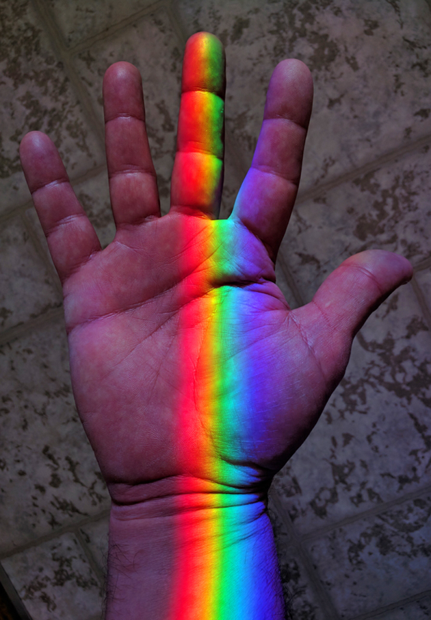 Rainbow colors from a Spectra sundial on the window sill kiss the maker's hand. Feel the color...Touch the rainbow!