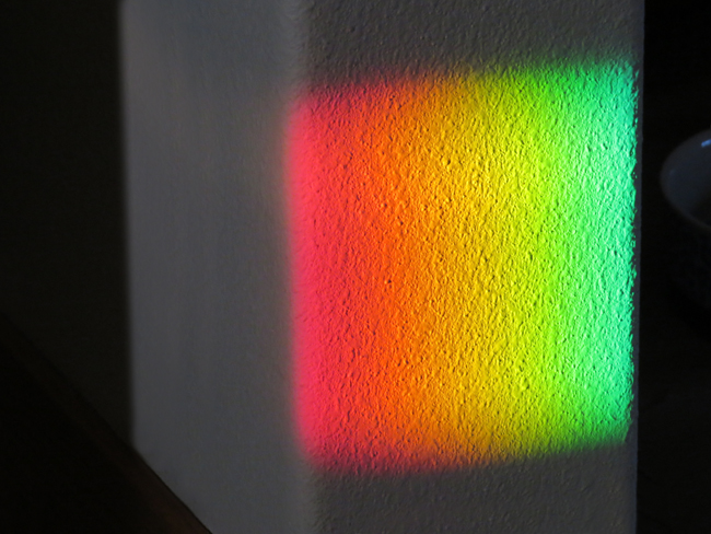 Rainbow colors on the wall from a rainbow sundial on the window sill